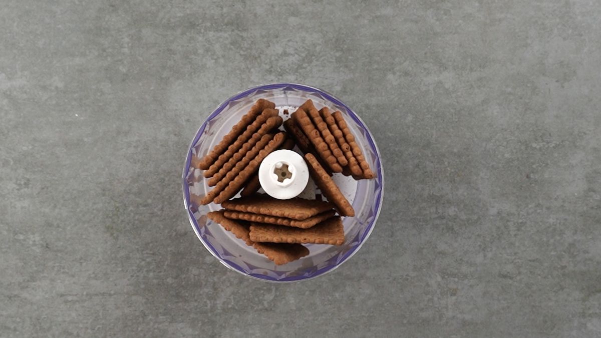 crackers in a food processor sitting on a gray table.