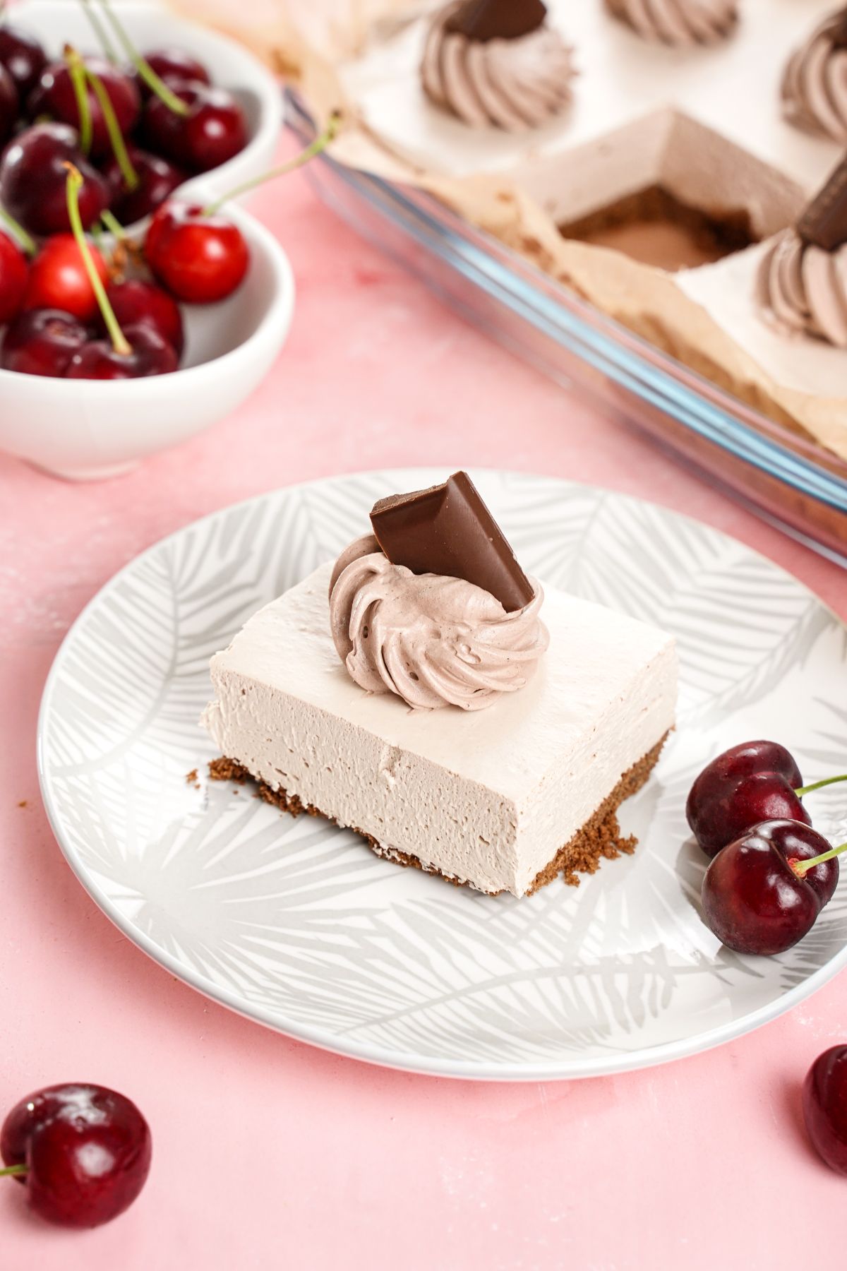 slice oc chocolate mousse bar on white plate sitting on pink table