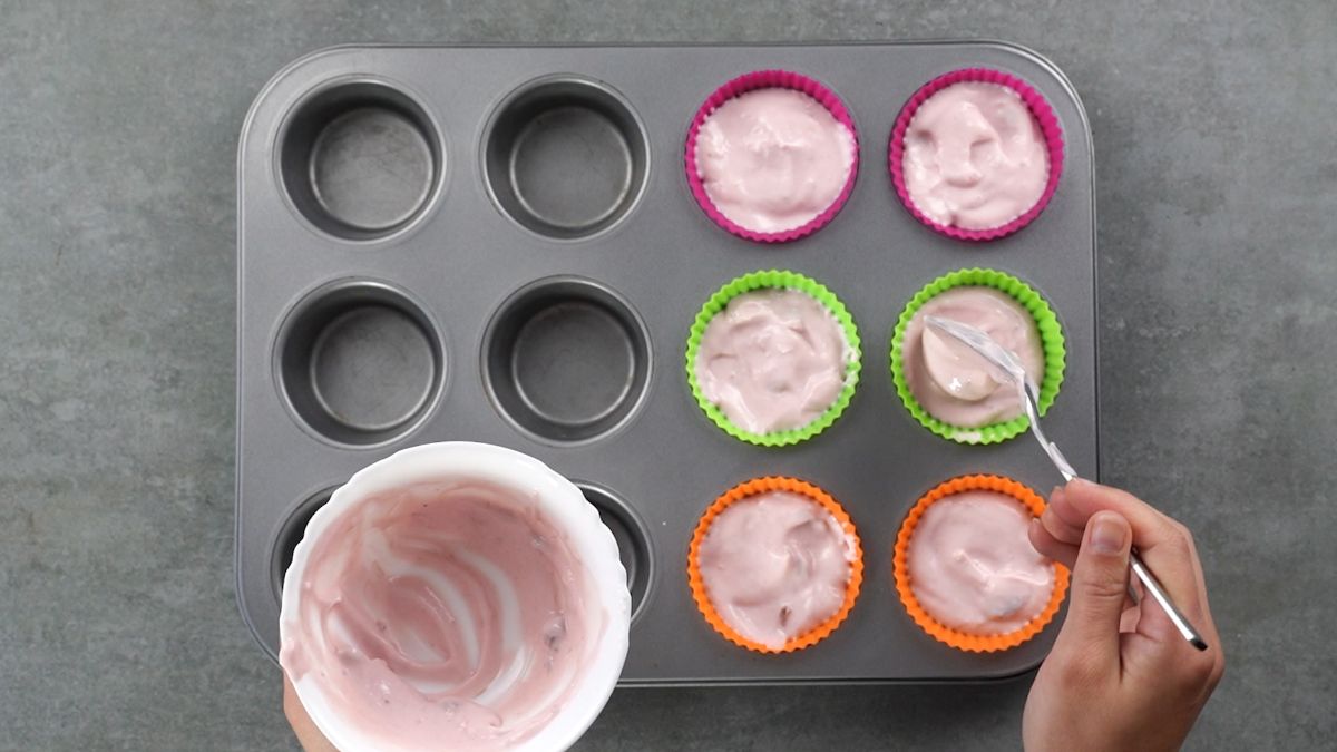 hand filling silicone muffin cups with yogurt