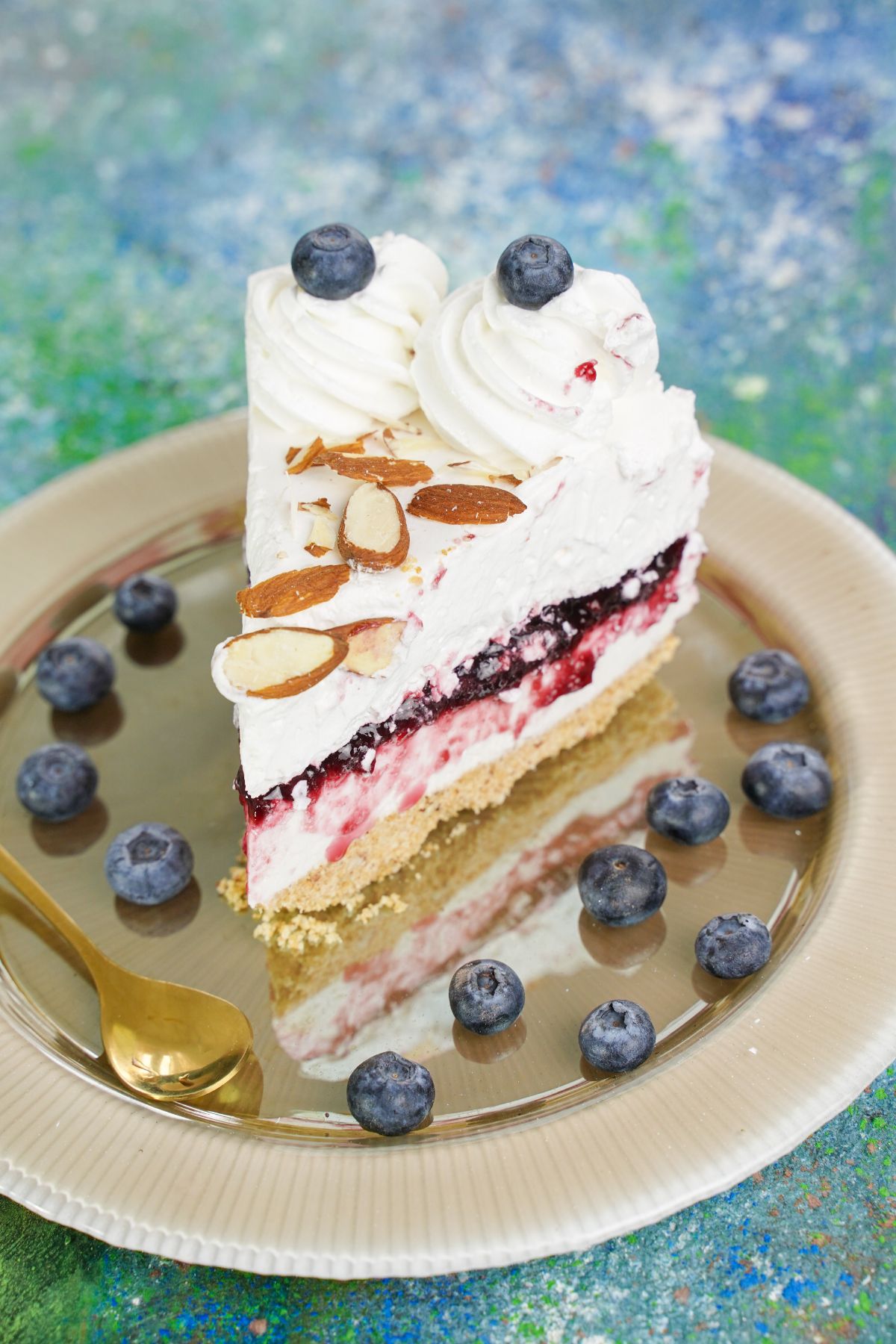 slice of blueberry cheesecake on gold plate sitting on blue marble table