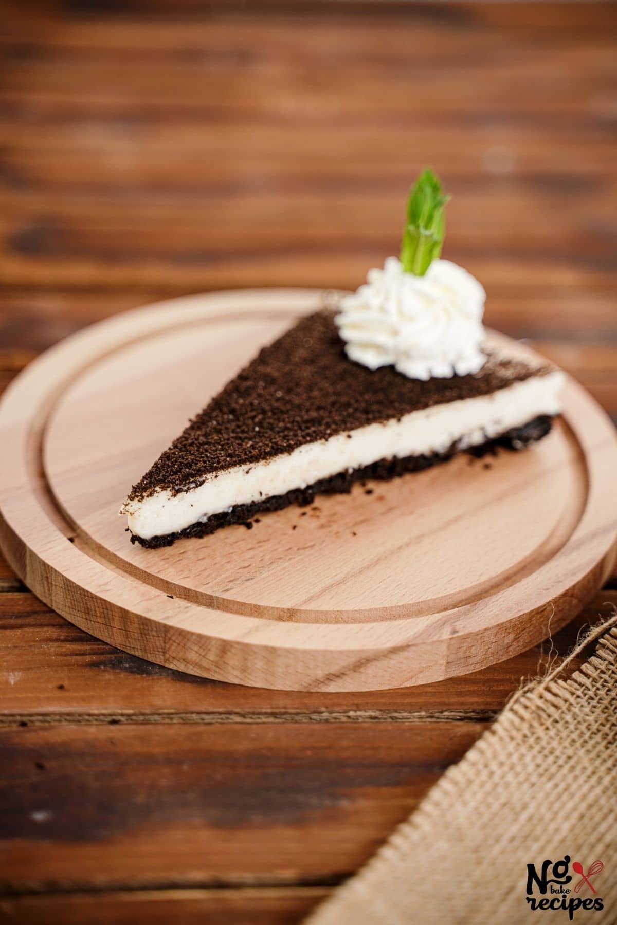 round wood plate on wood table topped with cheesecake slice