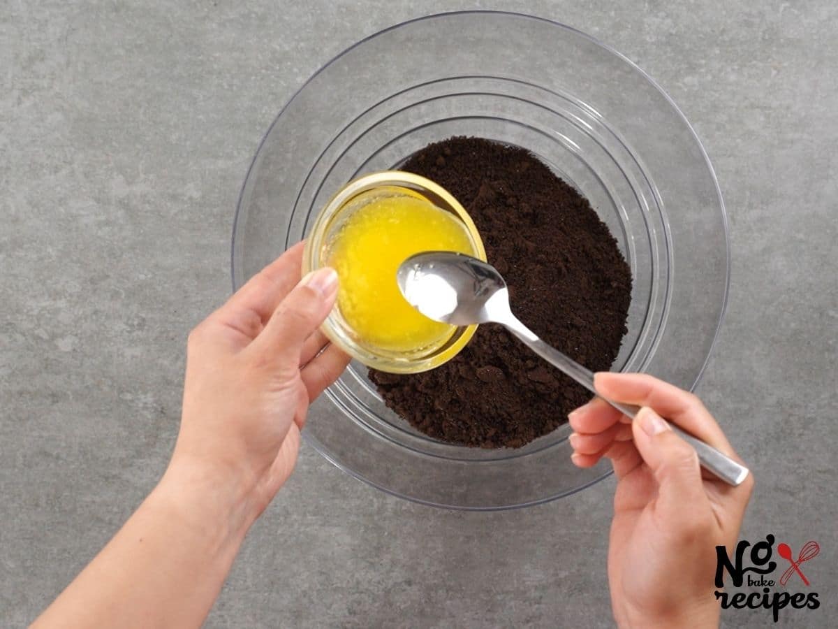 oreo cookie crumbs and butter in glass bowl