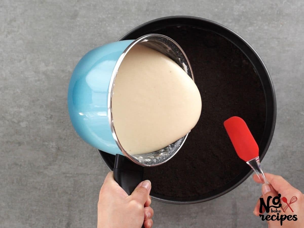 cheesecake in blue pan being poured onto cookie crust