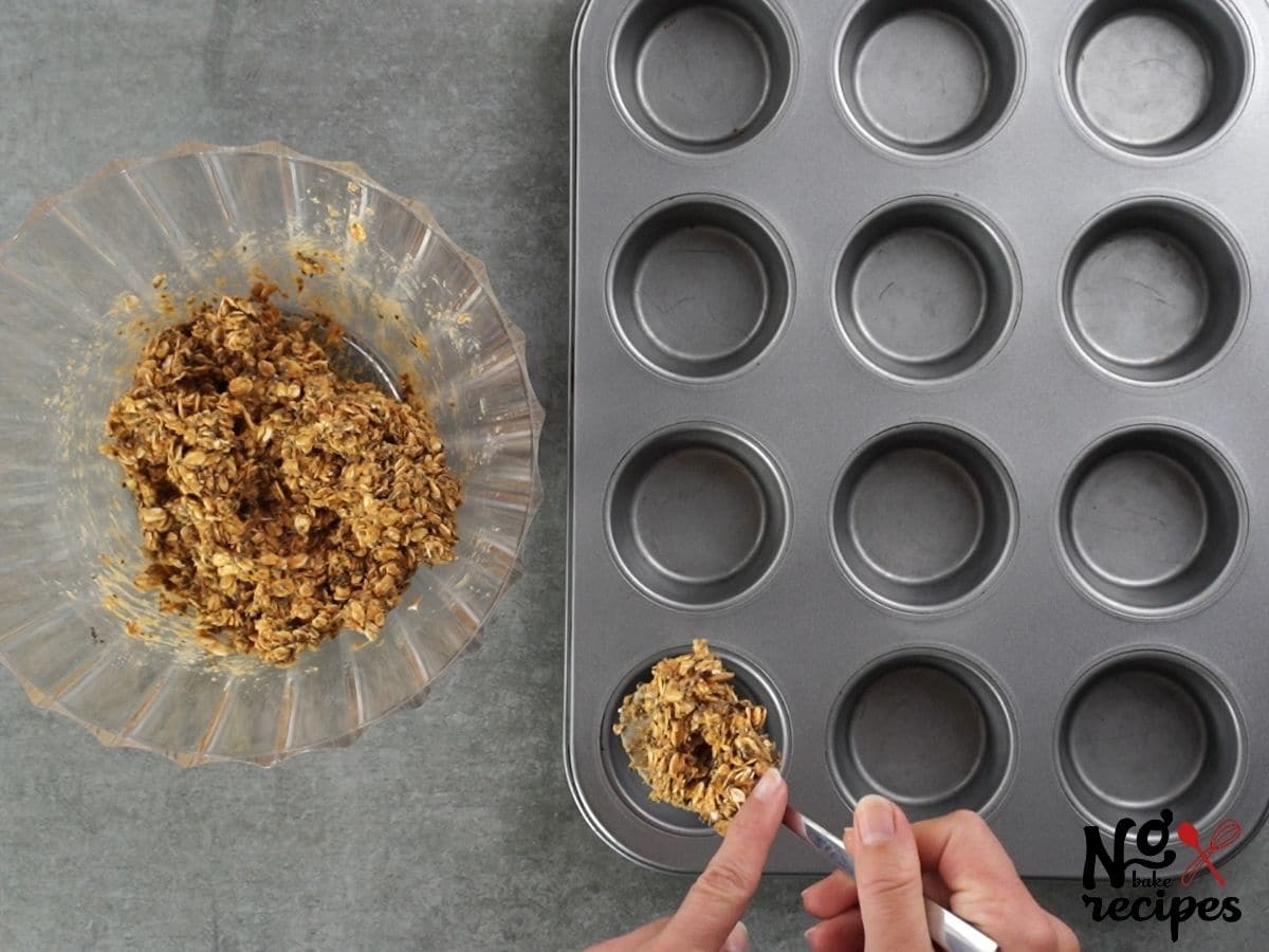 hand putting oatmeal mixture into muffin tin