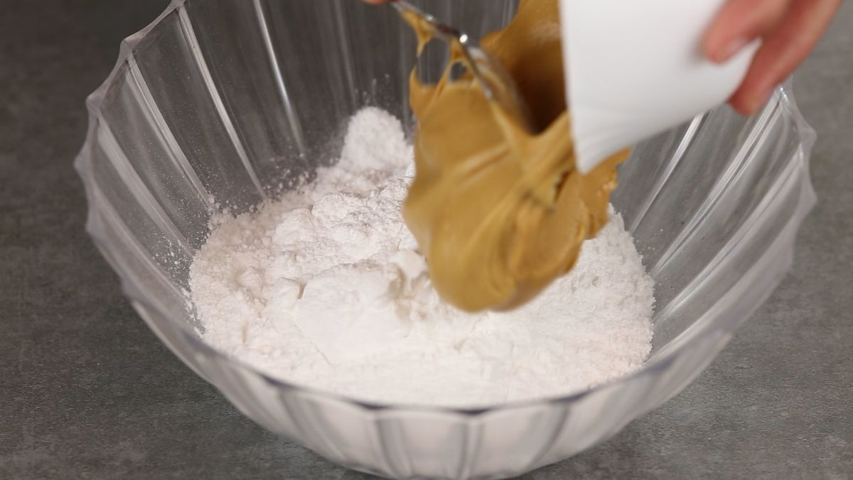 Adding peanut butter to glass bowl of powdered sugar