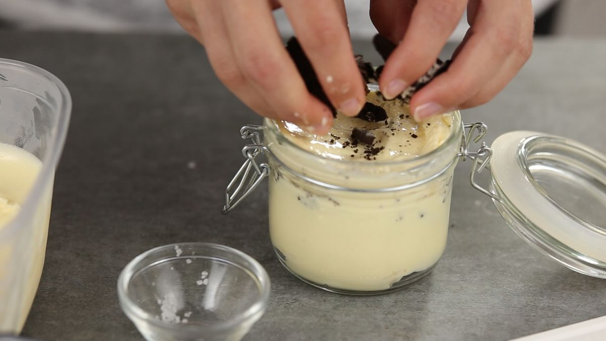 hands adding crushed oreos to top of parfait