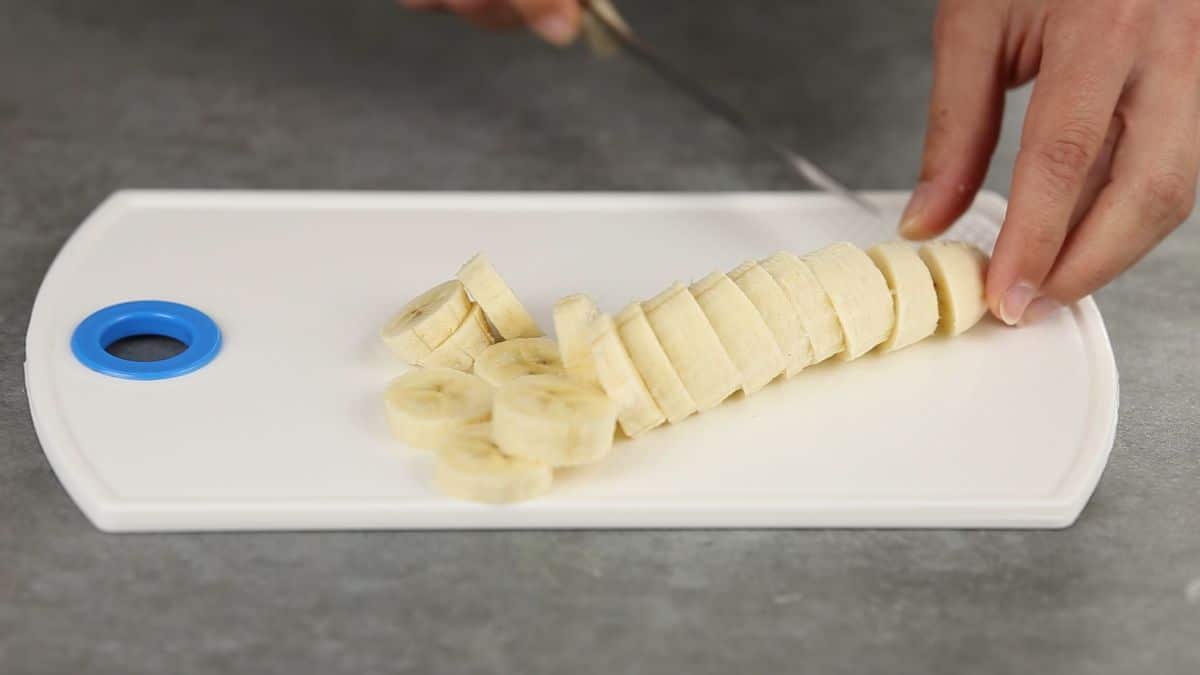 sliced bananas on white cutting board on gray counter