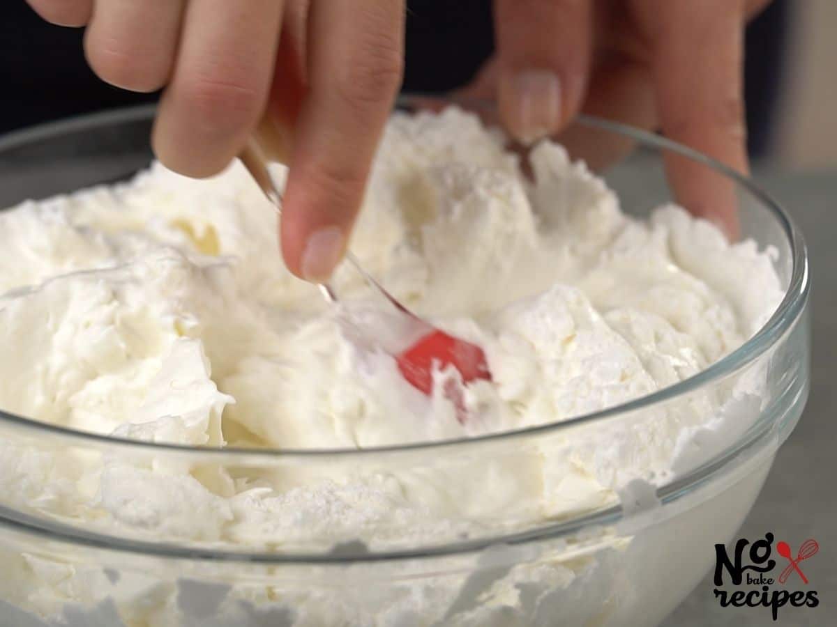 red spatula in cream cheese in glass bowl