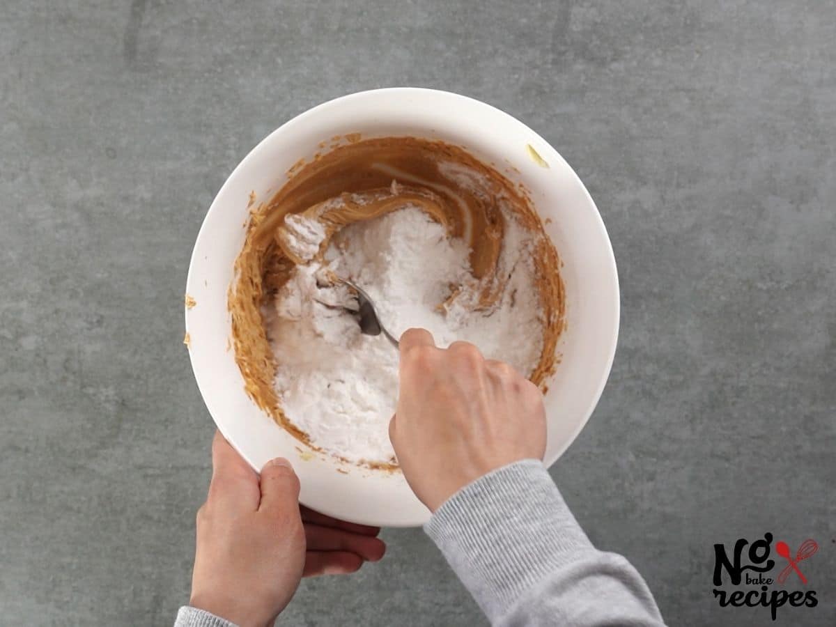 hand stirring powdered sugar into peanut butter