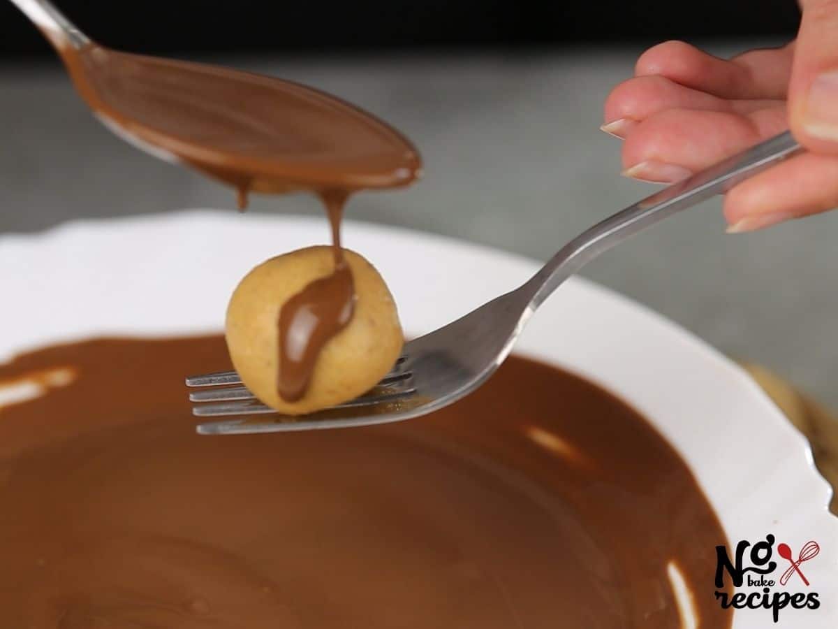 peanut butter ball on fork being covered in chocolate