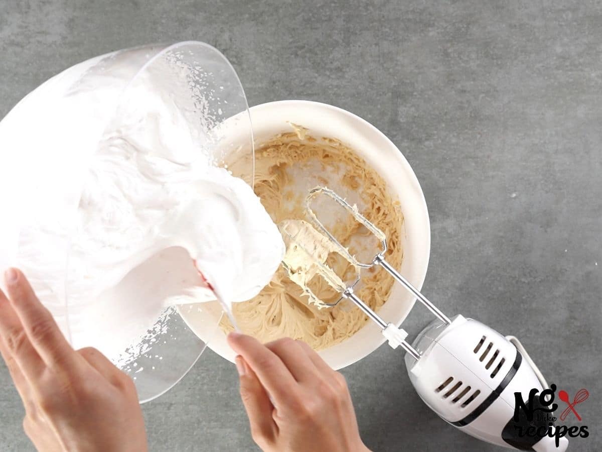hand adding cool whip to bowl of peanut butter