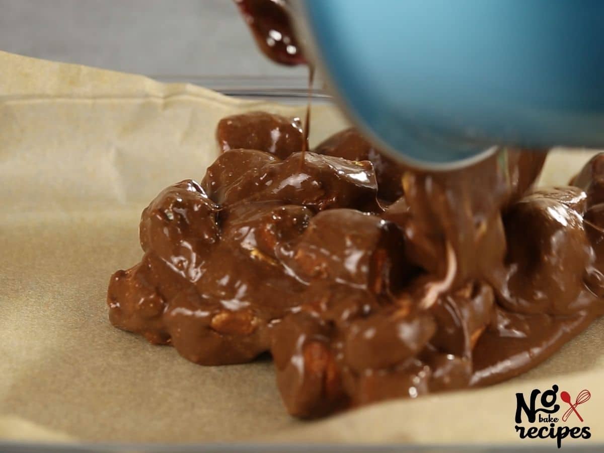 blue bowl pouring chocolate and marshmallows onto parchment paper