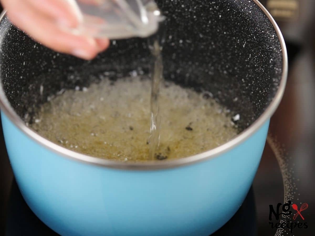 hand pouring liquid into bubbling mixture in pan