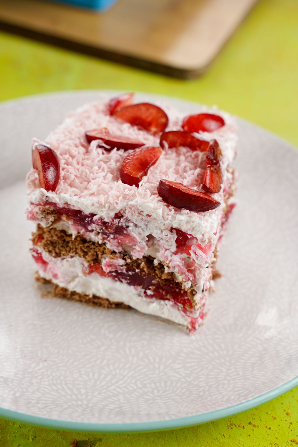 round white plate on yellow table topped by cherry icebox cake