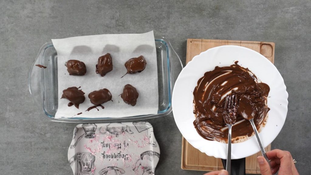 baking dish with parchment paper and bon bons before freezing next to bowl of chocolate