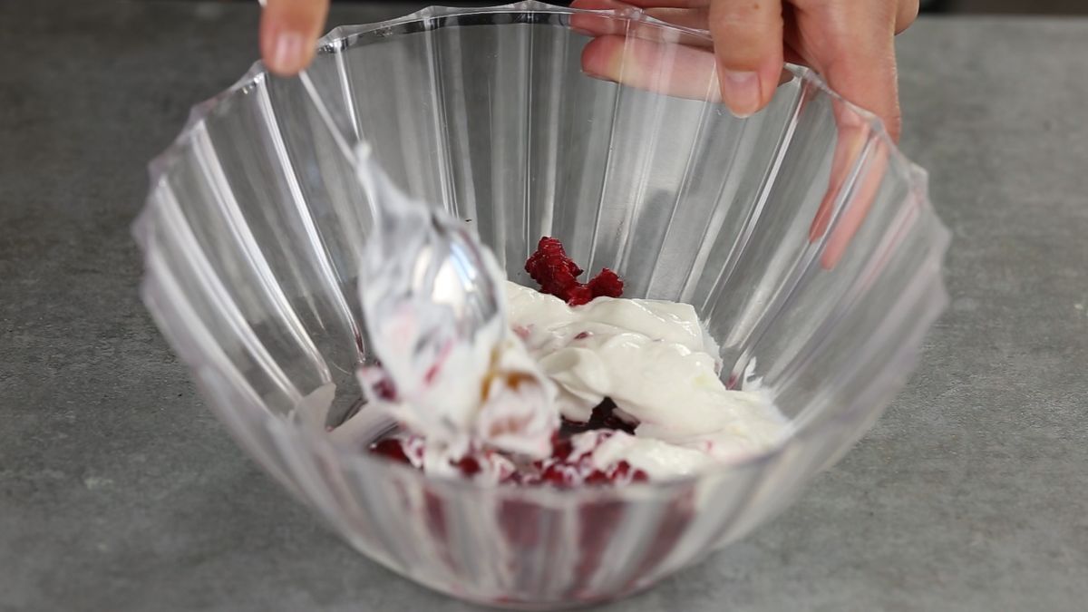 yogurt and berries being mixed in glass bowl