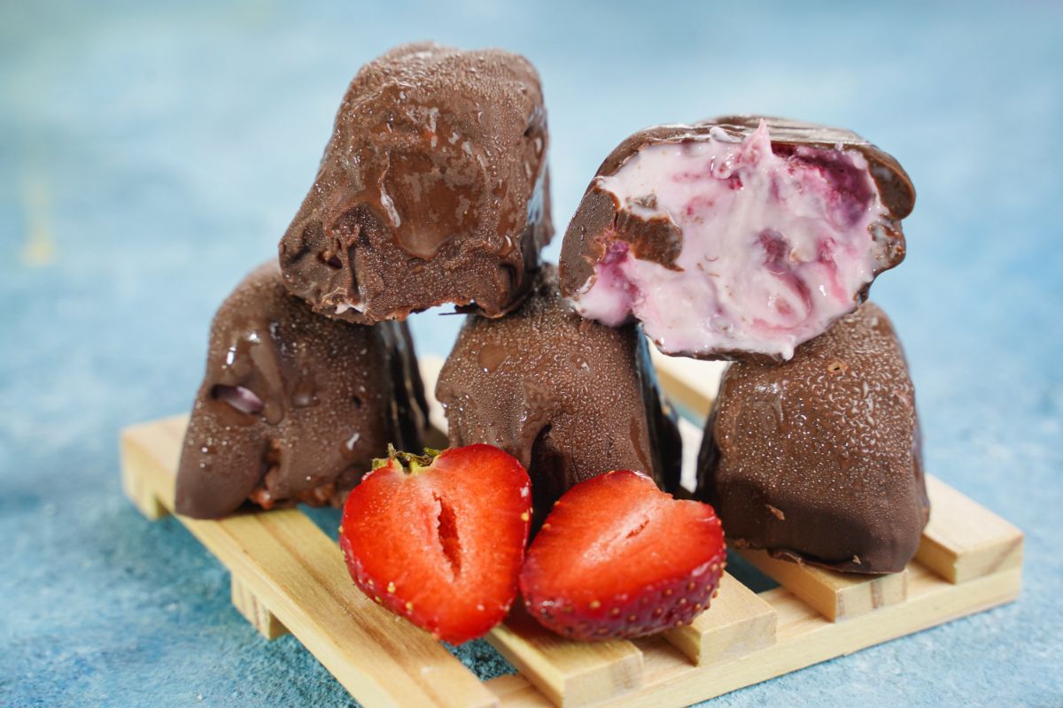 stack of bon bons with berries on wooden plate on blue table