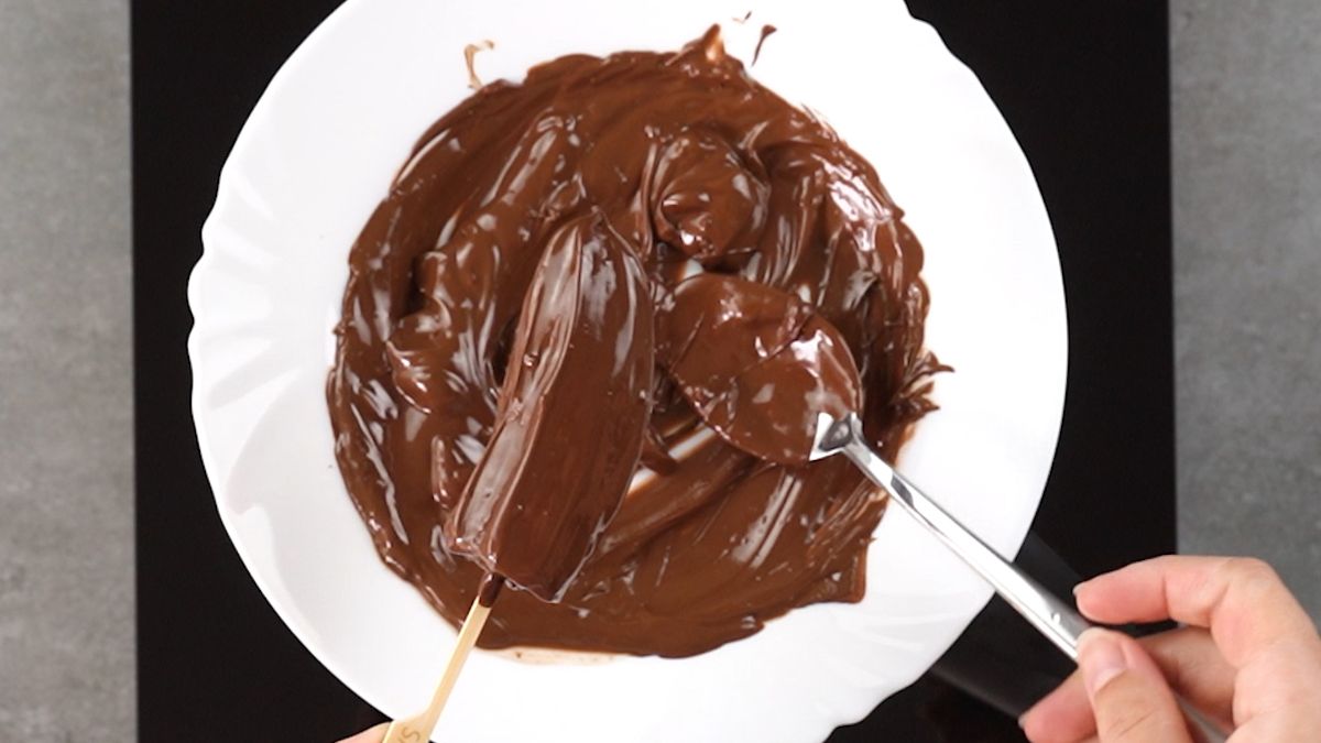 Dip the bananas into the liquid chocolate and cover it properly