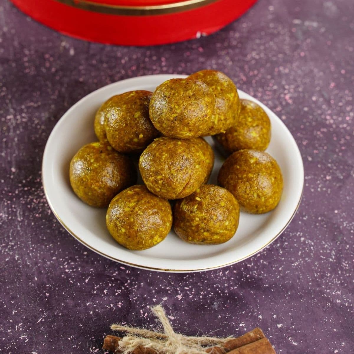 round white plate stacked with golden milk energy balls on purple table