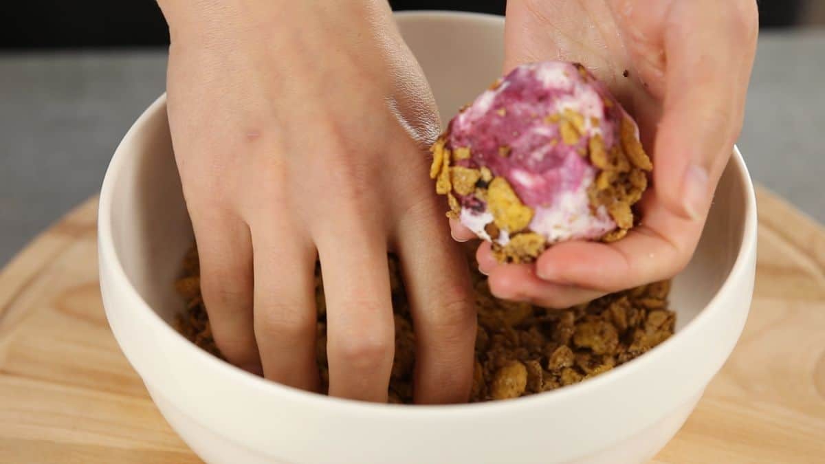 hand coating ice cream ball in cereal
