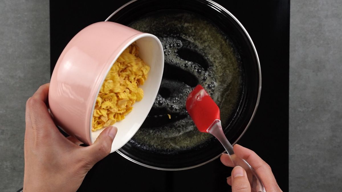 pouring corn flakes into skillet with butter