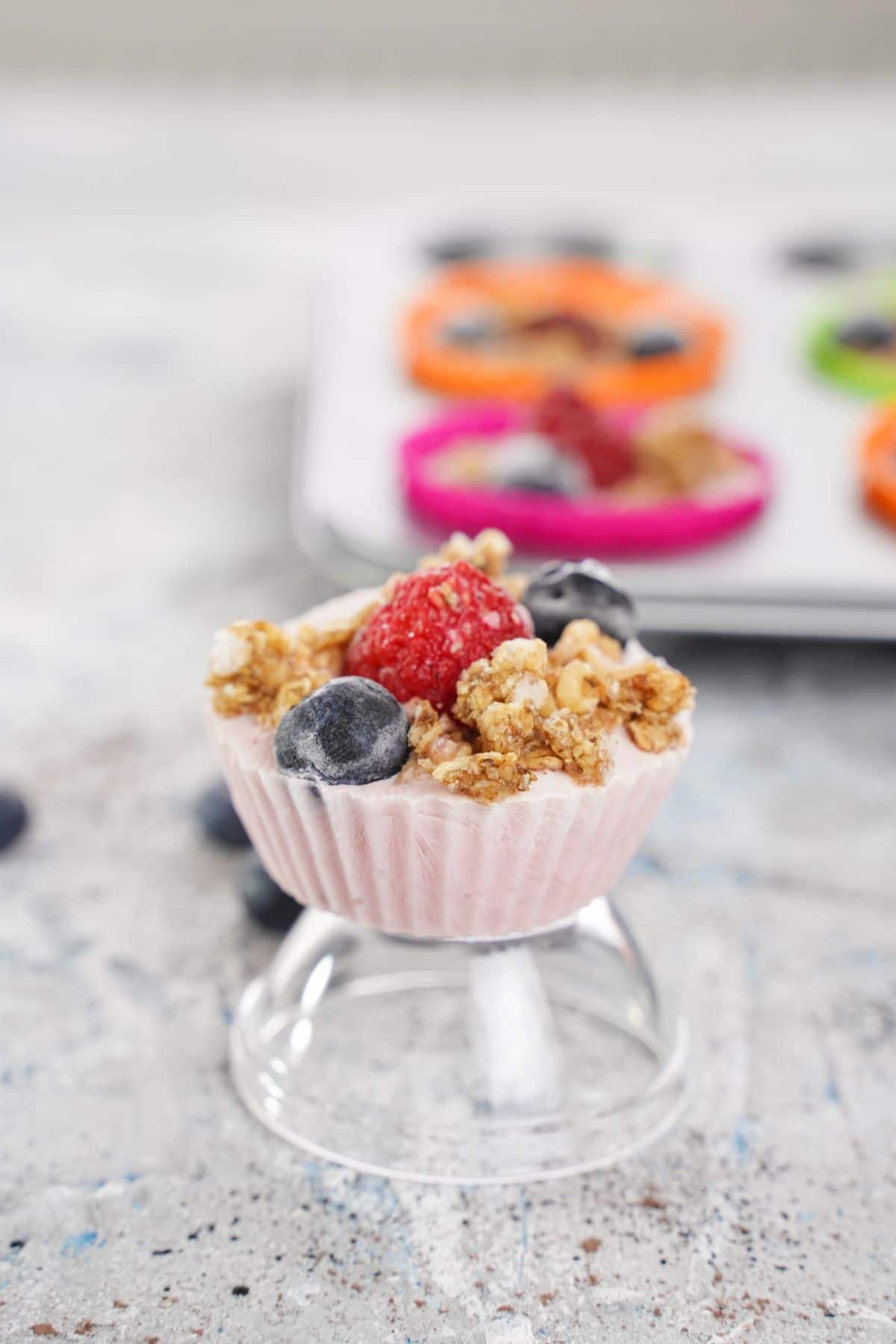 glass bowl with yogurt bite on top in front of muffin tin of yogurt bites