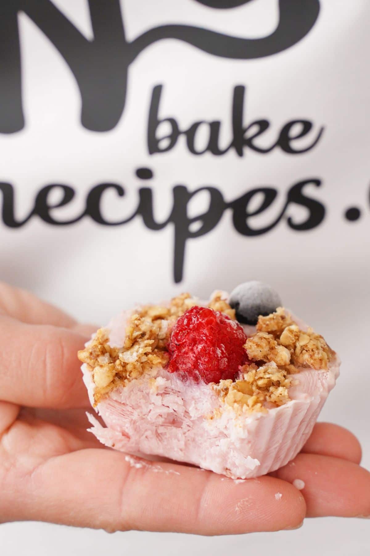 yogurt bite topped with granola and berries in hand