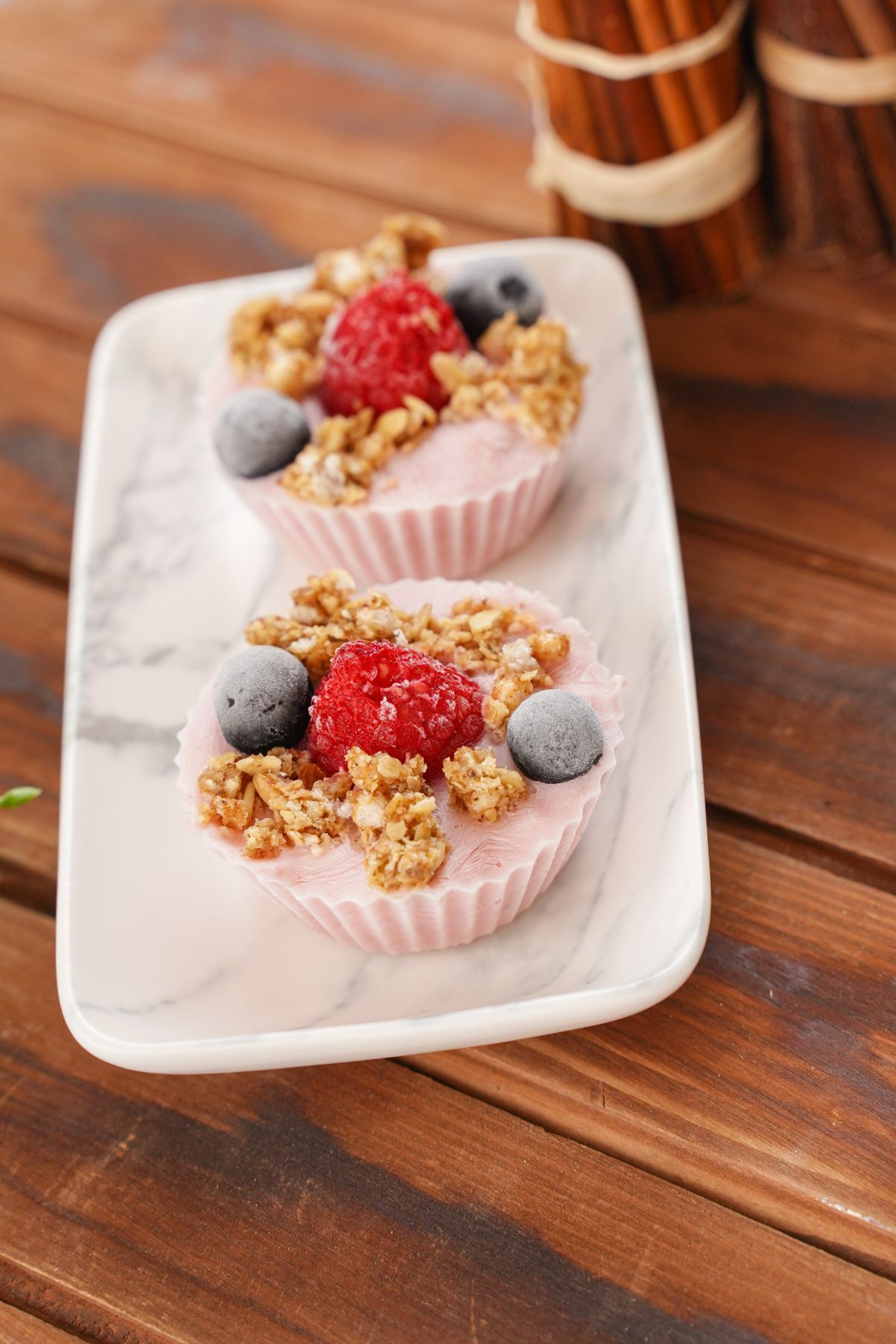 marble platter of frozen yogurt bites with berries on wooden table