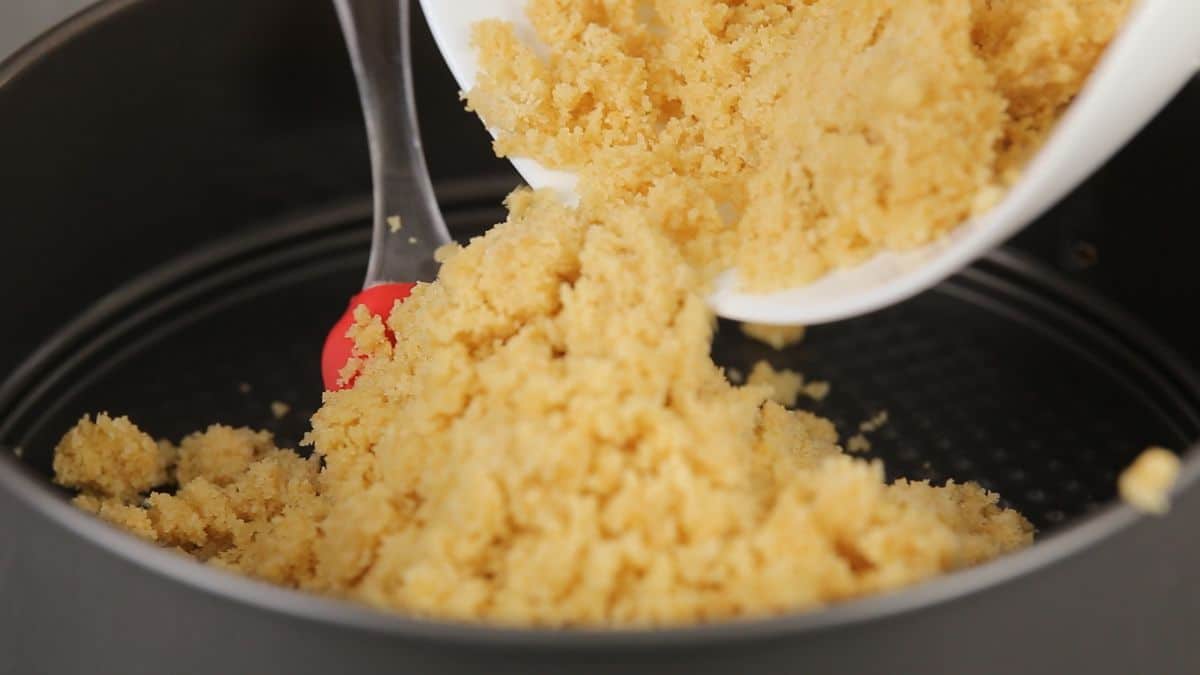red spatula scooping cookie crumbs into springform pan