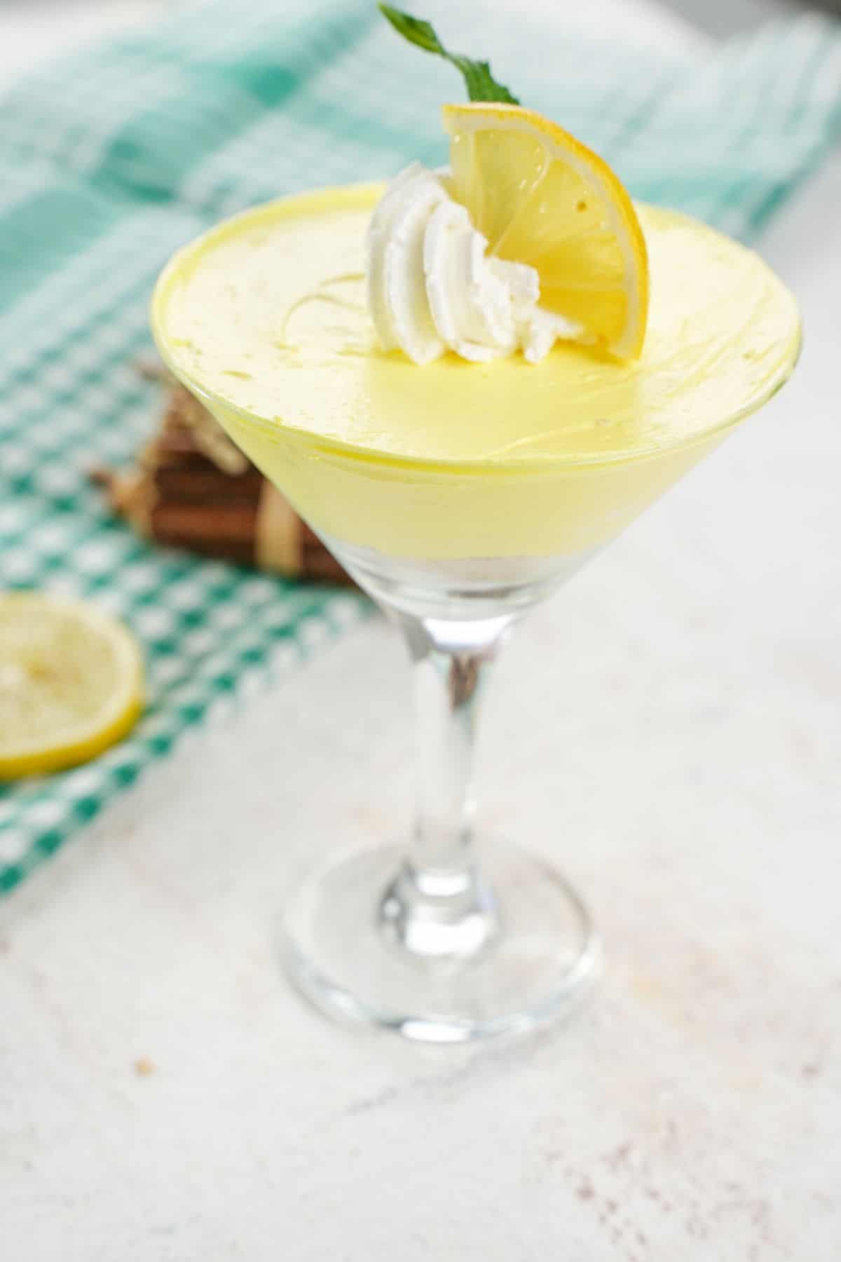 no-bake lemon cheesecake mousse styled in a martini glass with lemon and whipped cream topping