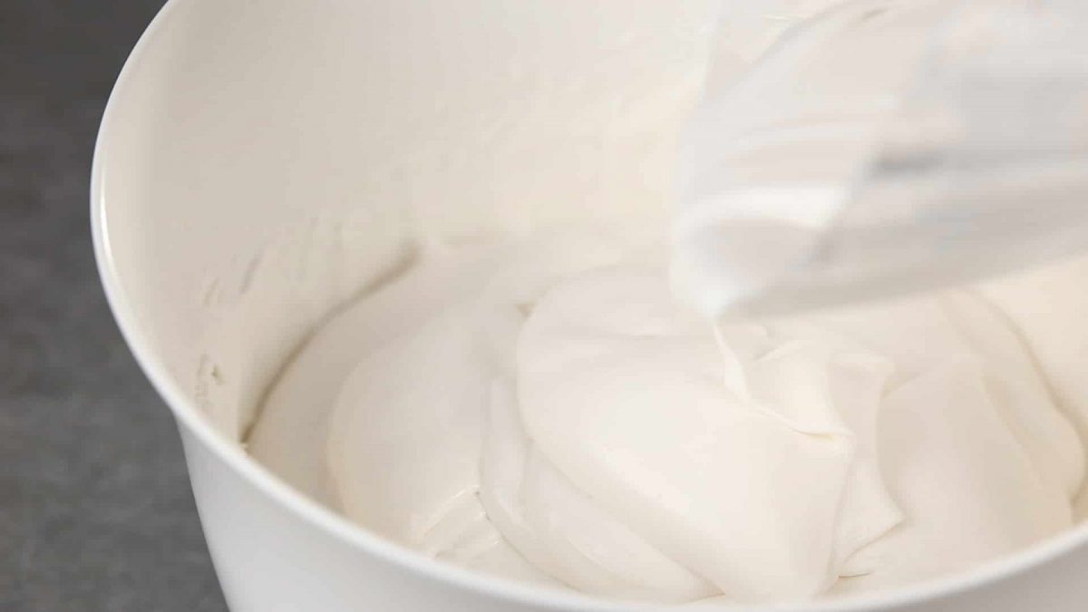 mixing cream cheese and whipping cream together in white bowl