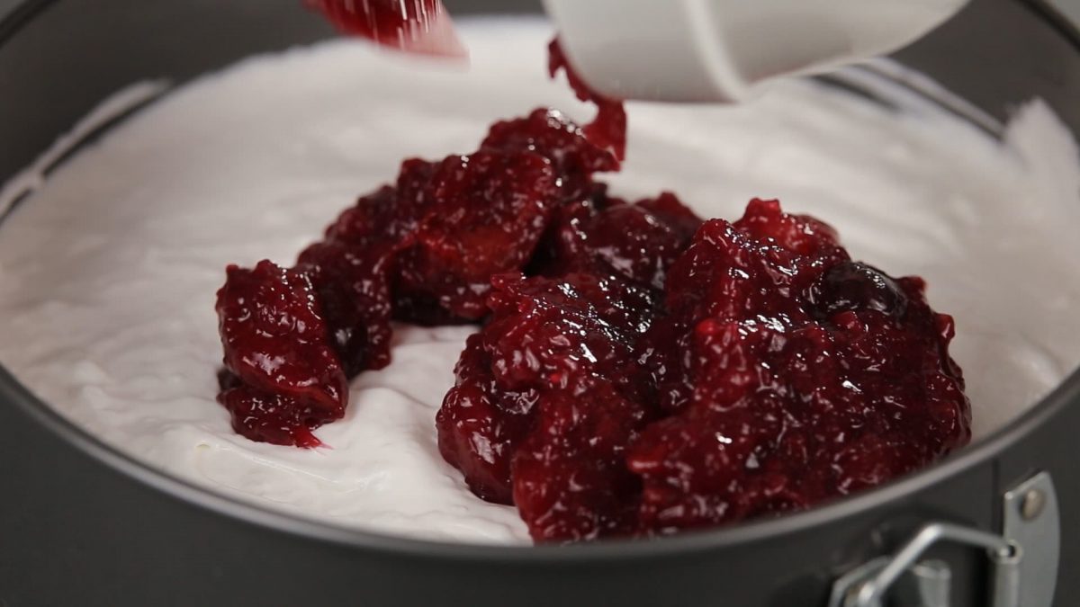 pouring cherry pie filling over the top of cheesecake