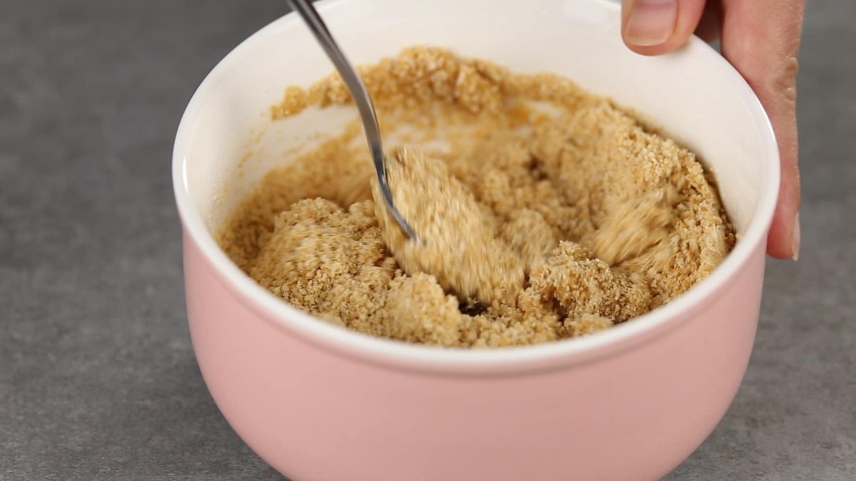 spoon mixing cookie crumbs in pink bowl