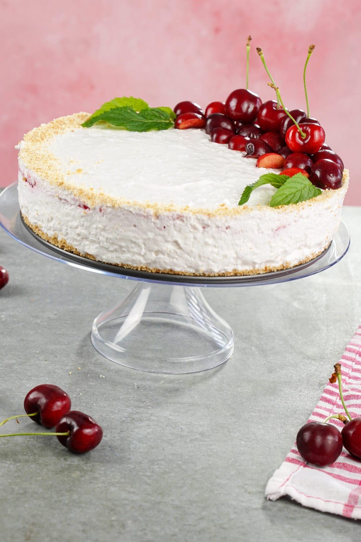 cheesecake on glass cake stand on gray table