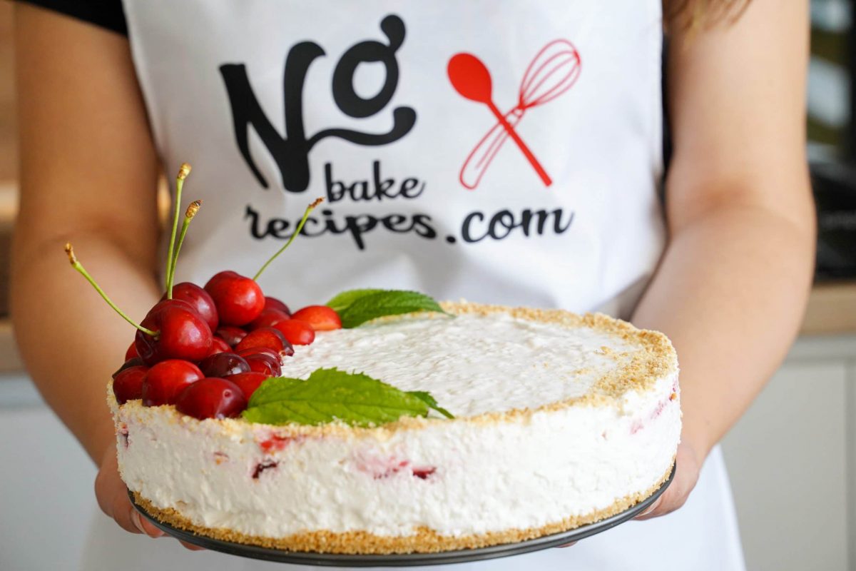 woman in white apron holding cherry cheesecake