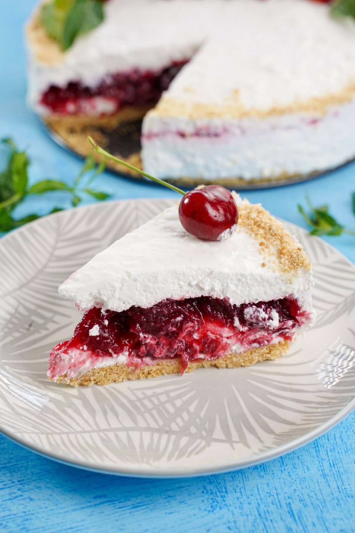 slice of layered cheesecake on white plate on blue table