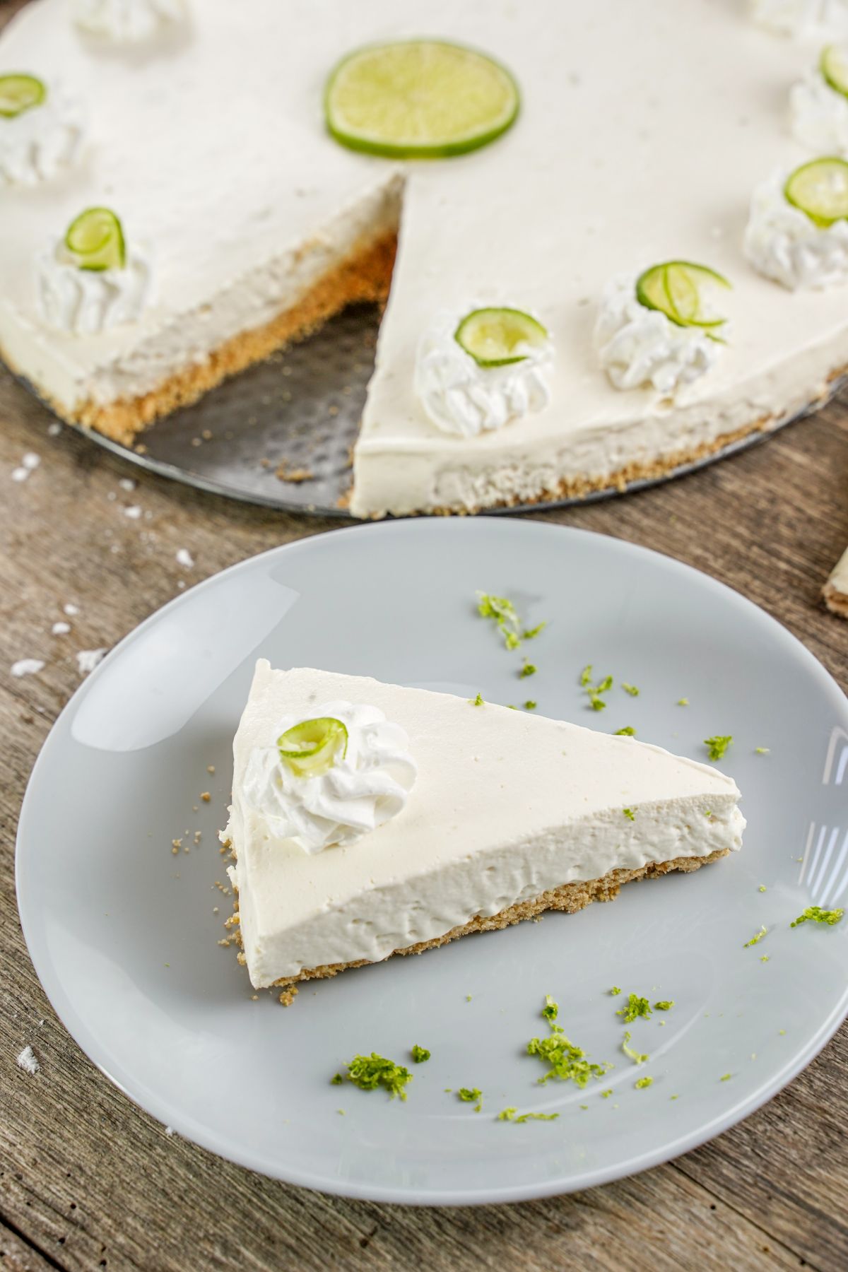 slice of lime tart on light blue plate next to whole pie