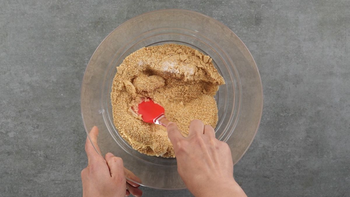 hand stirring cookie crumbs with red spatula