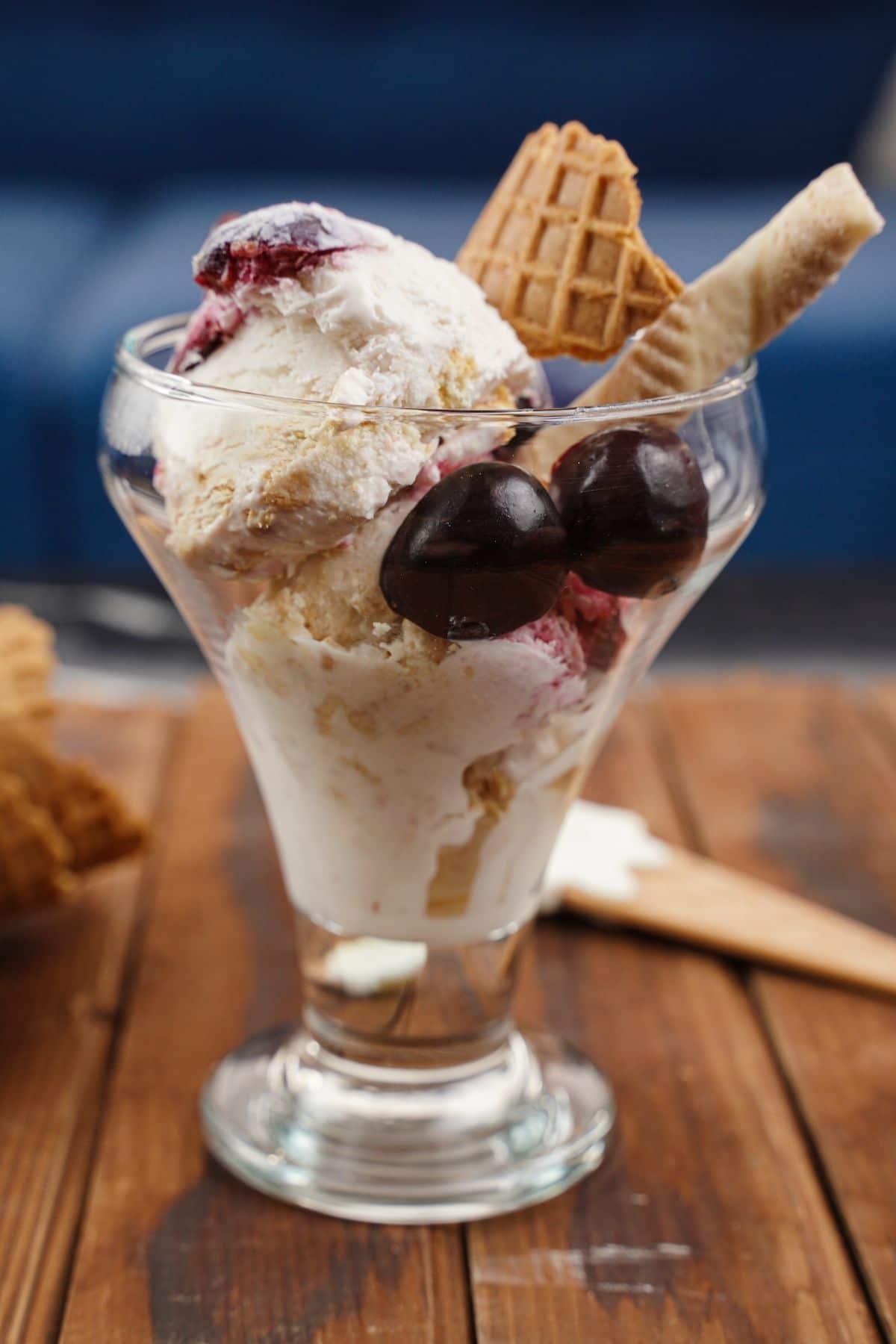 no-churn cherry cheesecake ice cream in a bowl with cherries and waffle cone pieces