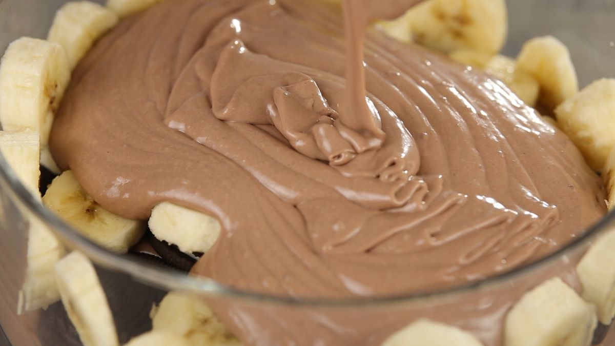 Pouring chocolate pudding over cookies and bananas