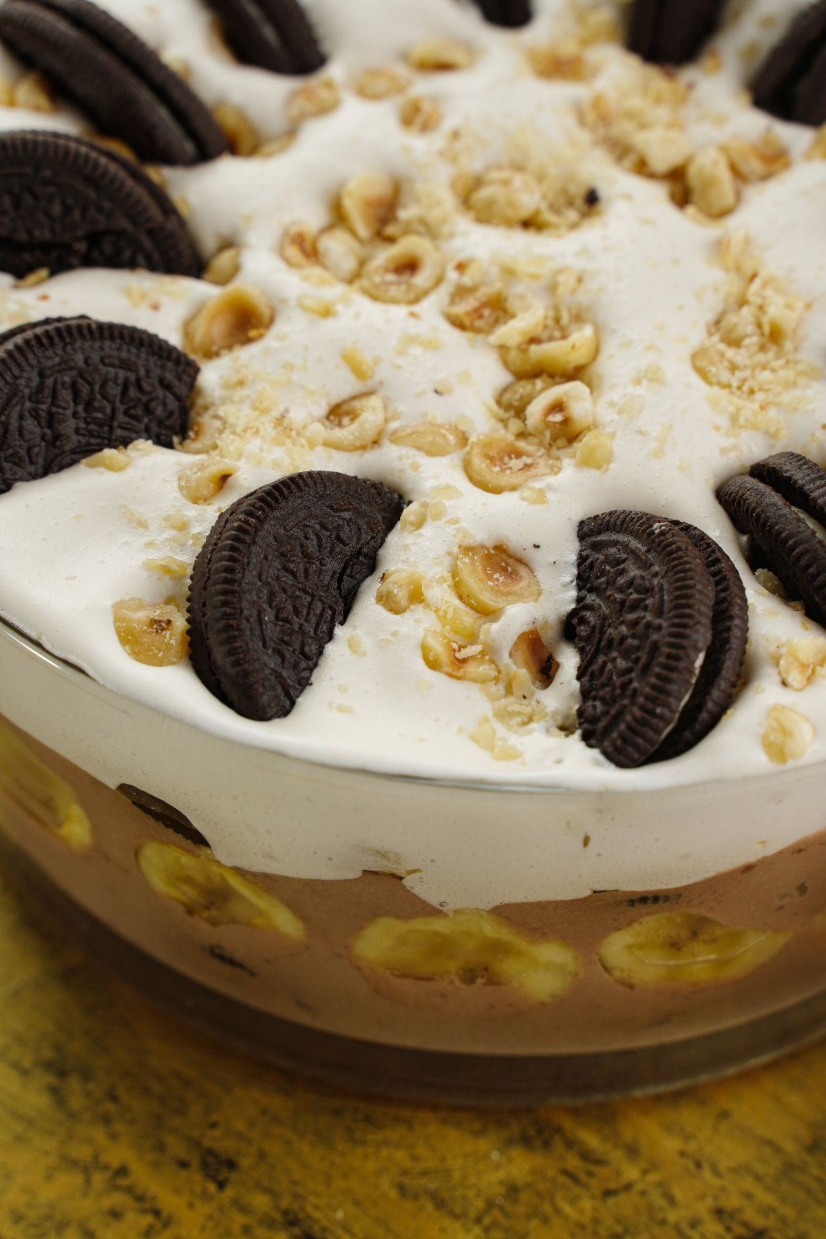 top of trifle with pudding bananas and oreos on top with hazlenuts on whipped cream