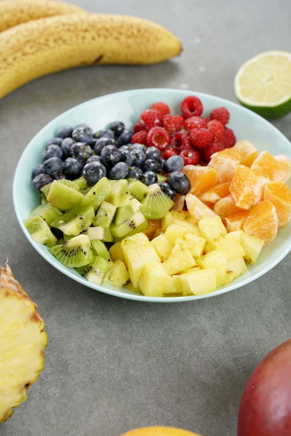 rainbow fruit salad with honey dressing on a grey table