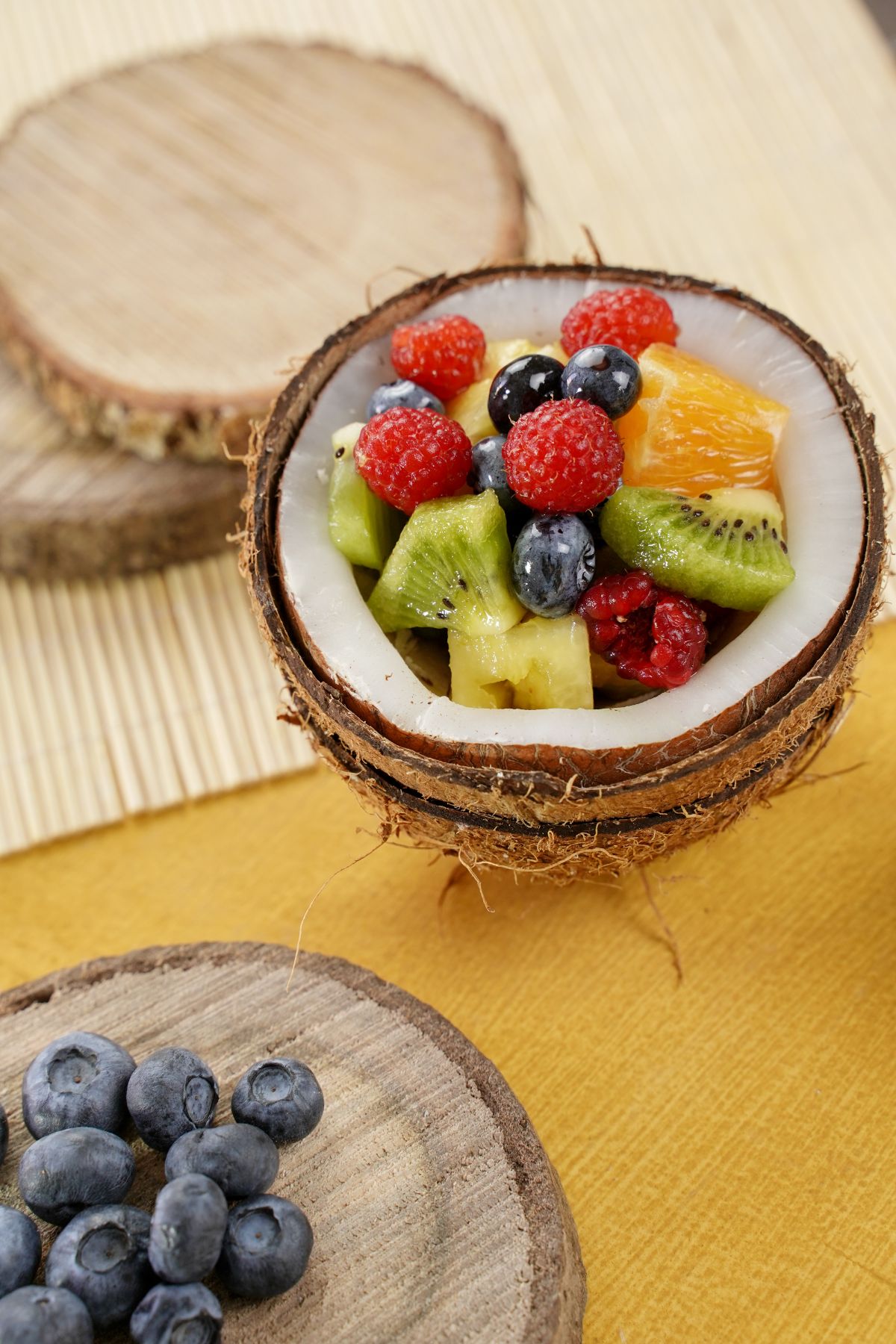 Rainbow Fruit Salad with Honey Dressing served in a coconut with some fresh blueberries