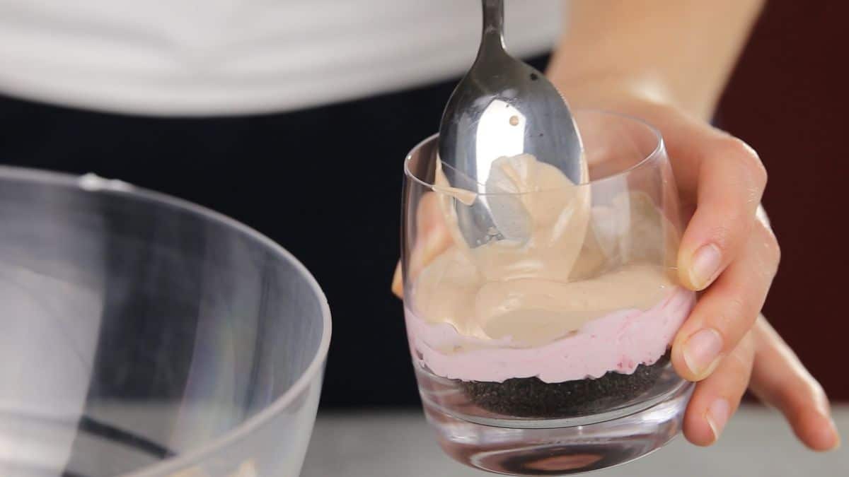 spoon spreading nutella cream on top of raspberry cream