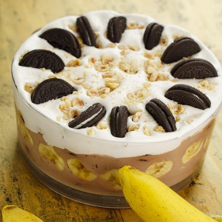glass trifle bowl filled with pudding and bananas topped with whipped cream and cookies