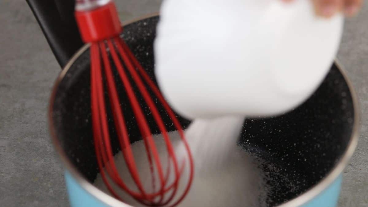 red whisk in saucepan with flour and sugar