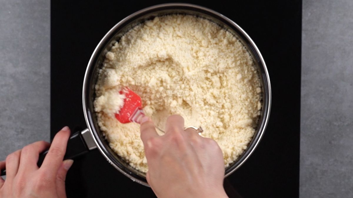 crumb mixture in skillet being stirred with red spatula