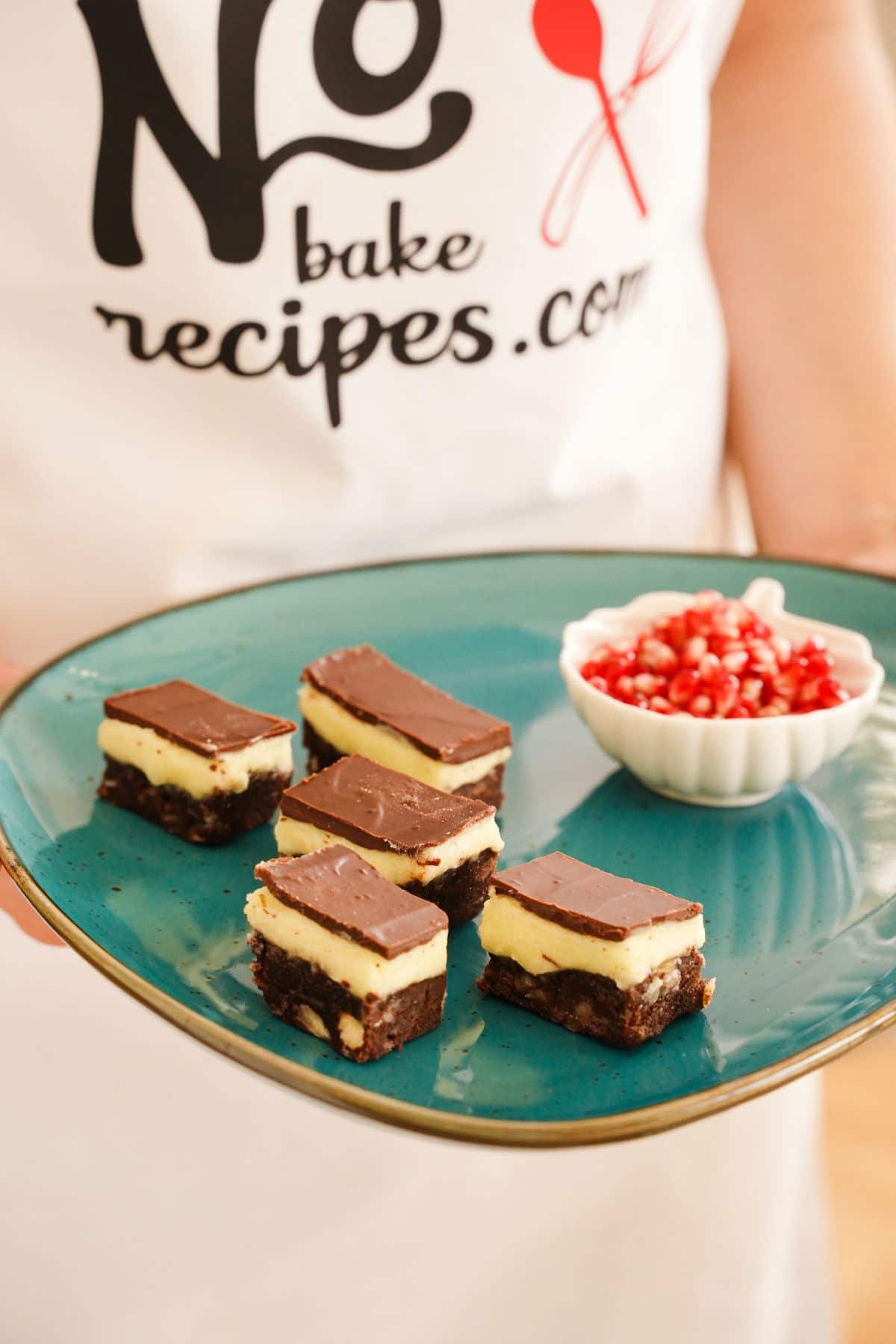 Copycat Nanaimo Bars served with fresh pomegranate in a bowl
