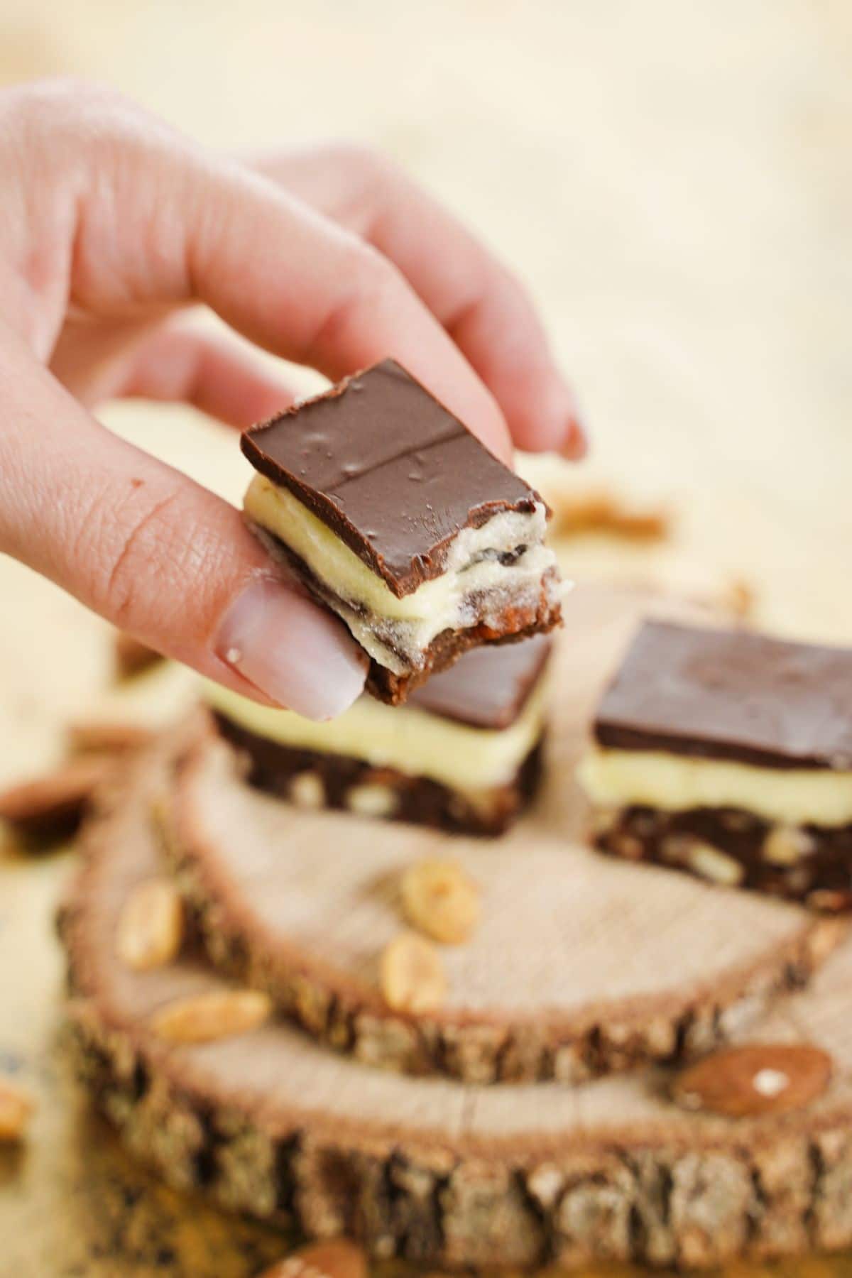 A bite of Copycat Nanaimo Bars with almonds in the background
