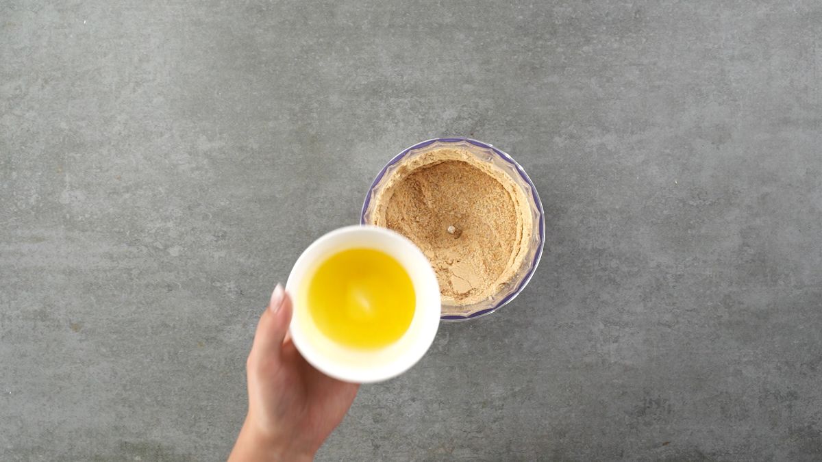 Graham crackers crumbs are mixed with melted butter in a bowl